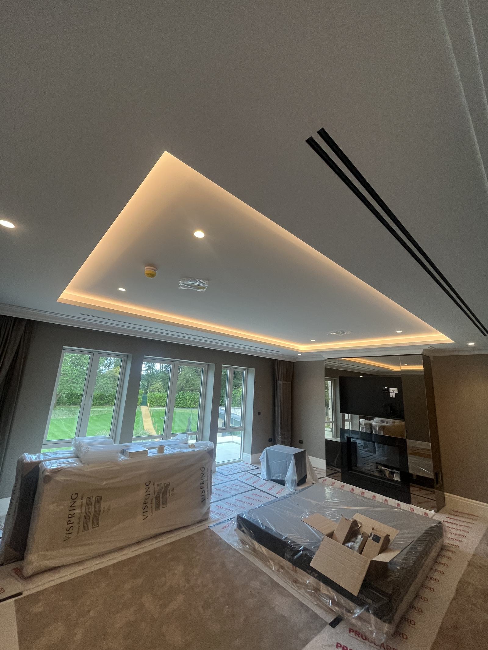 Principal bedroom with cove-lit ceiling and flush linear diffusers