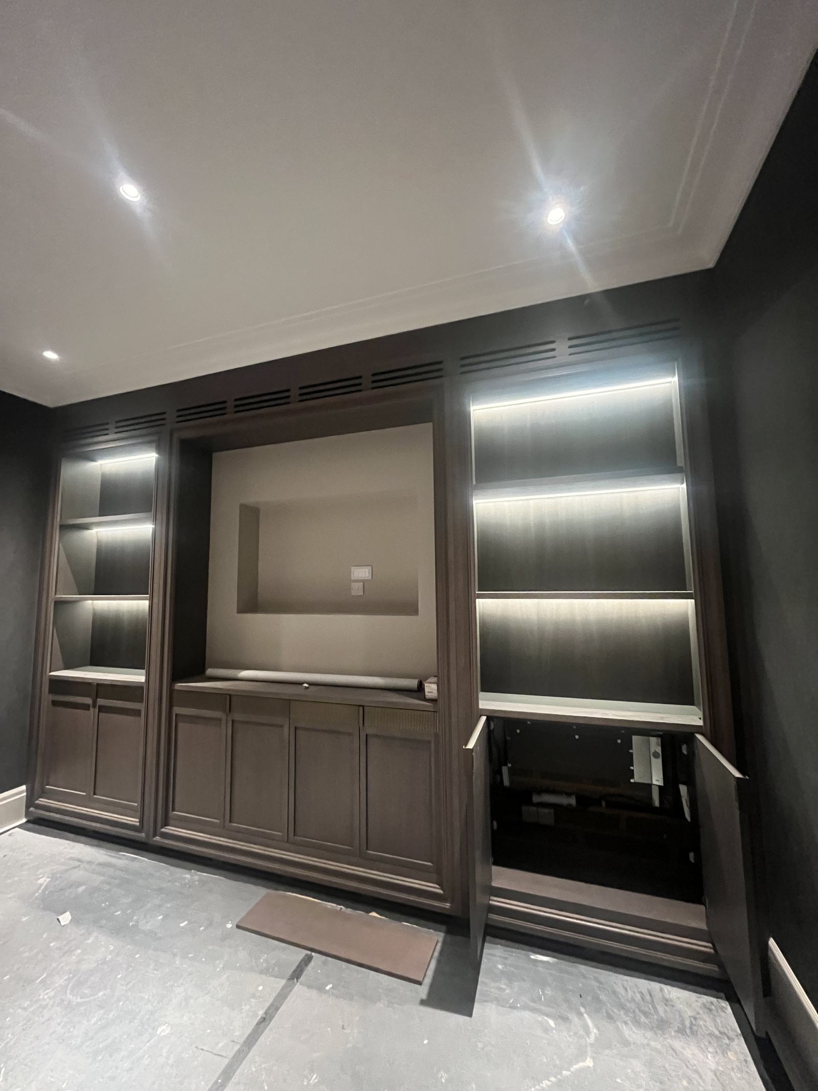 Ventilation grilles concealed within dark timber media joinery
