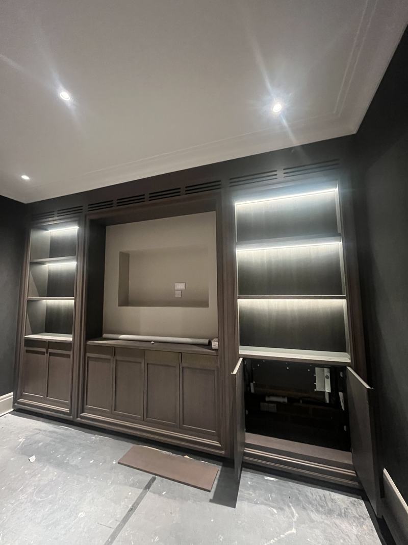 Ventilation grilles concealed within dark timber media joinery